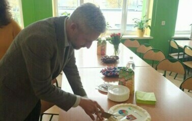Pan Prezydent Zgierza kroi tort w sali lekcyjnej. 
