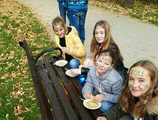 Uczennice na ławce w parku wsp&oacute;lnie jedzą posiłek.