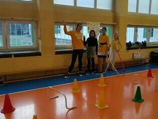 Uczniowie wykonują zadania sportowe na sali gimnastycznej.